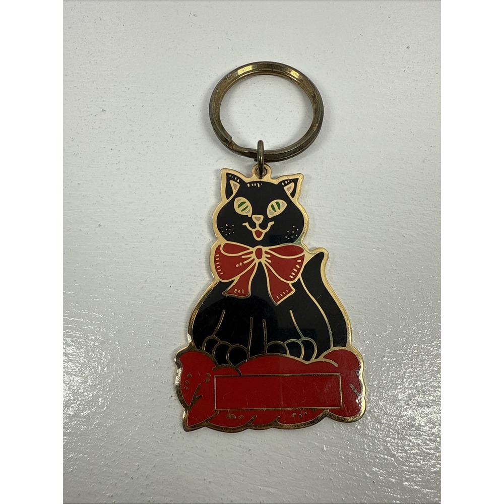 Black cat enamel keychain with gold-toned metal accents and‎ a red bow